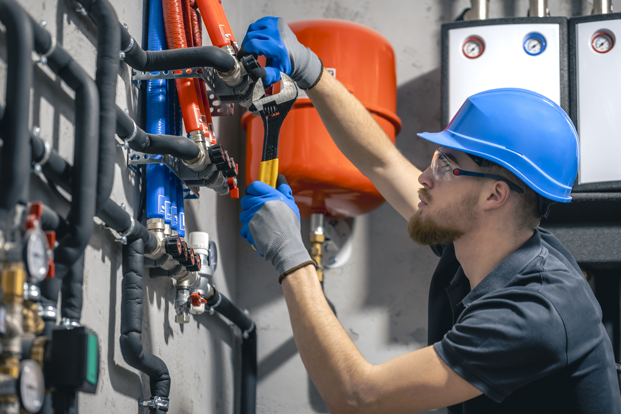 Plumber adjusting pipe with wrench in a commerical setting - image