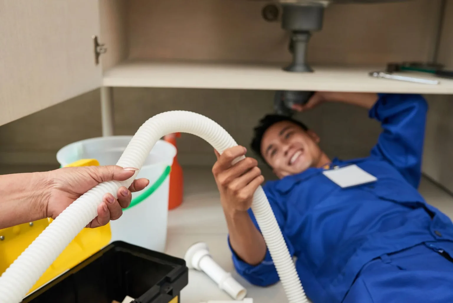 Plumber working under sink image